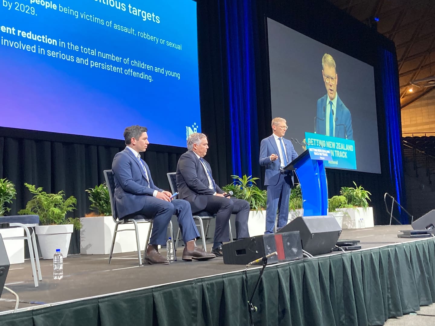 Justice Minister Paul Goldsmith speaks to the National Party conference with Police Minister Mark Mitchell and National MP James Meager (left) at the Manukau Due Drop Events Centre. Photo / Claire Trevett