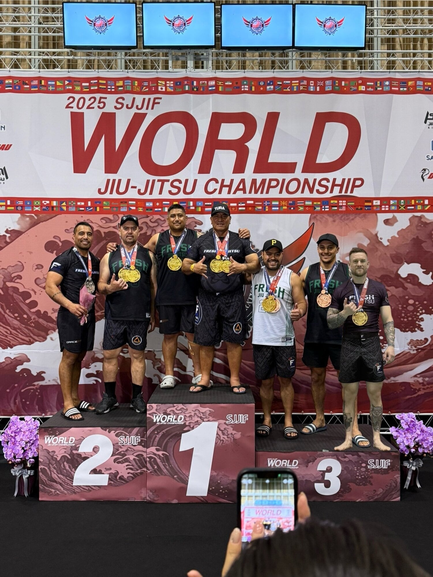  Fresh Jiu-Jitsu Rotorua’s adult team on the podium in Japan. Graeme Marukore (left) Clint Paenga, Tere Marsters, Arona Marsters, Taiawhio Hohua, Otene Melrose and Mick McLeod. Photo / Supplied
