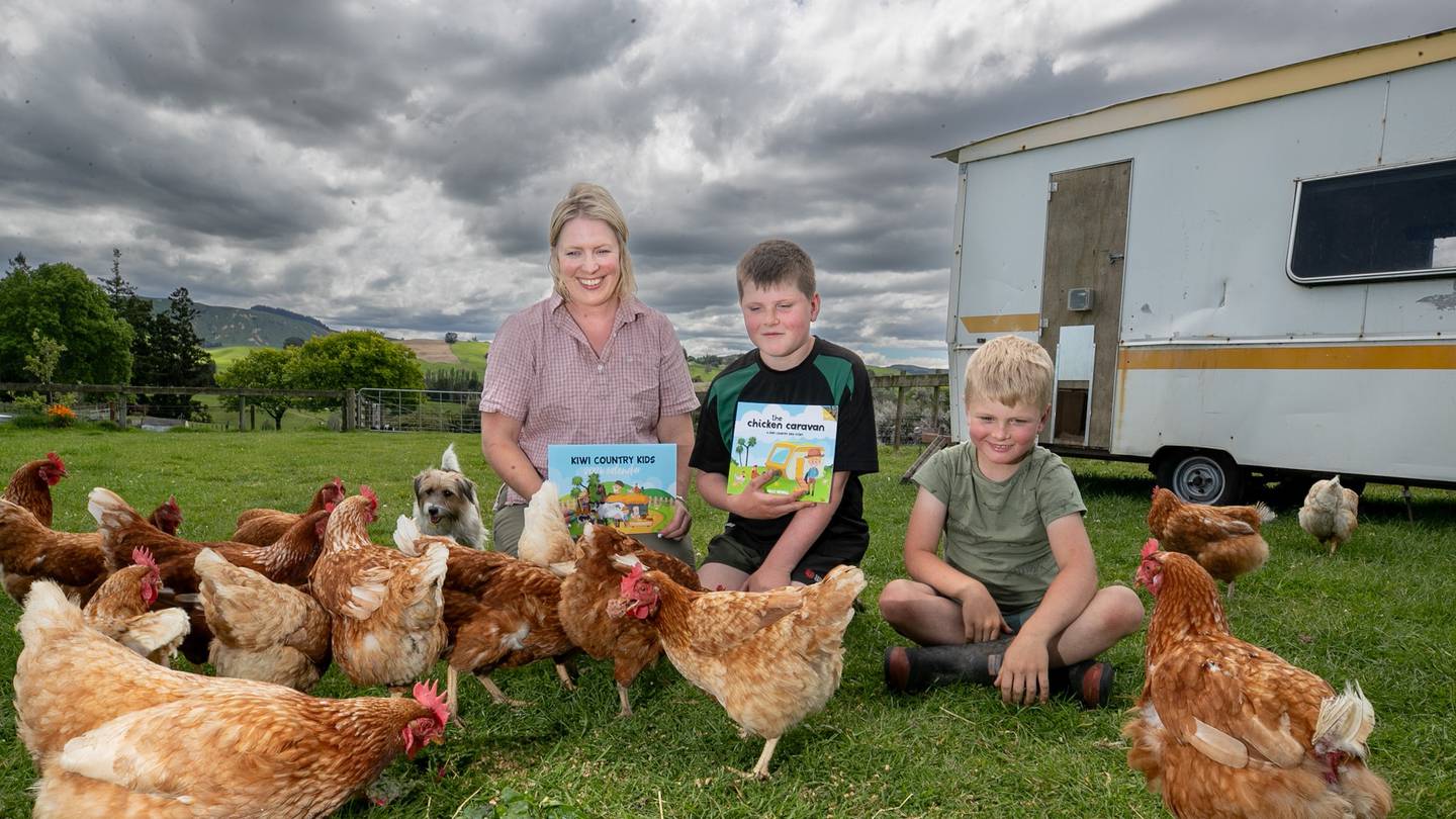 Patoka farmer and vet Sally Newall with her new book The Chicken Caravan and the Kiwi Country Kids calendar sits among the family's hens with two of her three sons,  Oscar and Ted.  Photo / Warren Buckland