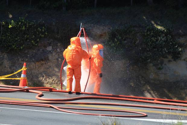 Workers are hosed down after dealing with the aftermath of a truck crash at Pukerua Bay. Photo / Kyle Mitchell