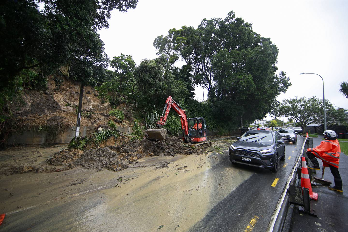 Workers clean up a slip on West End Rd in Herne Bay after storms and flooding in Auckland. Photo / Alex Burton