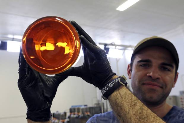 Julian Cabrera, factory manager at New Earth Biosciences, holds up a large glass beaker of golden-coloured, fully-refined CBD oil in Salem, Oregon. Photo / AP