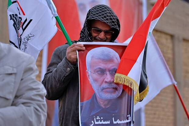 A man grieves while holding a poster of Abu Mahdi al-Muhandis, deputy commander of Iran-backed militias who was killed in a US airstrike in Iraq, on Friday. Photo / AP
