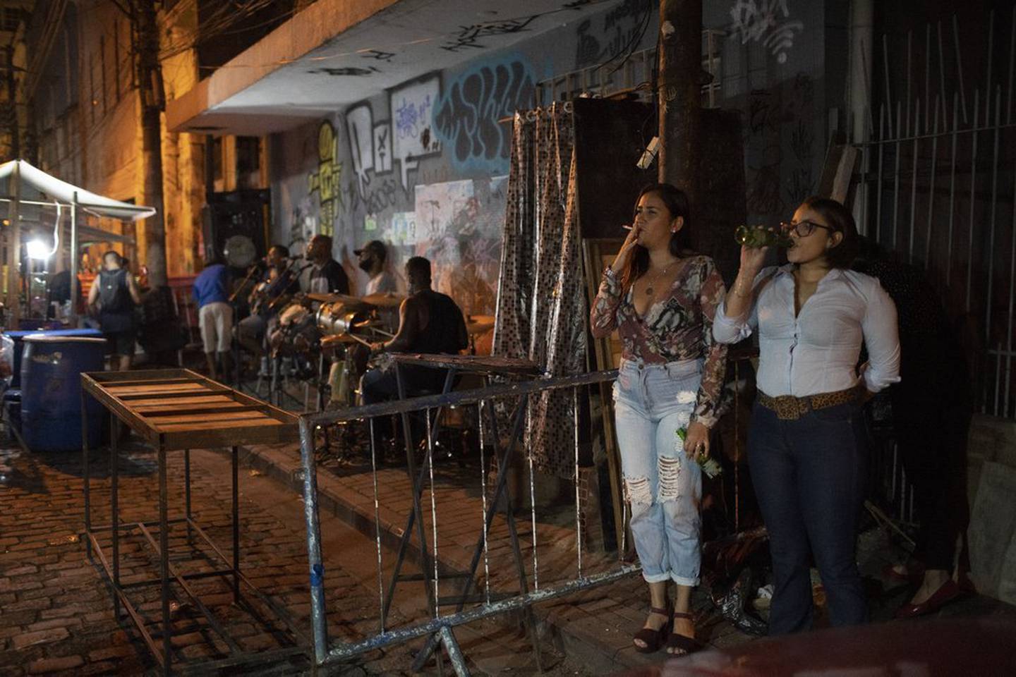 Two friends stand on the streets of Rio de Janeiro, Brazil, listening to samba band Atitude Nossa. Photo / AP