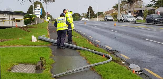 A damaged street light and skid marks on the grass at the scene.