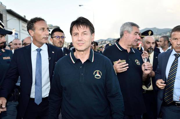 Italian Premier Giuseppe Conte, center, arrives at the site where the Morandi highway bridge collapsed in Genoa. Photo / AP 
