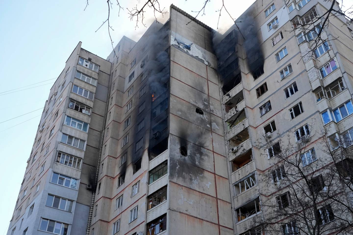 3月25日在乌克兰哈尔科夫发生袭击后，在燃烧的多层公寓的墙上可以看到俄罗斯炮击造成的洞。照片/美联社